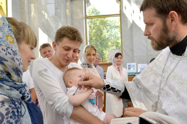 Kaliningrad, russland - 04. August 2013: Ein orthodoxer Priester salbt einen Aal aus der Hand eines Säuglings, bevor er ins Wasser taucht. Taufritual — Stockfoto