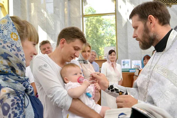 KALINININGRAD, RUSIA - 04 DE AGOSTO DE 2013: Un sacerdote ortodoxo unge una anguila infantil antes de sumergirse en el agua. Rito de bautismo —  Fotos de Stock