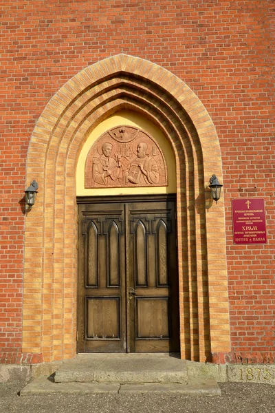 Arched portal of the main entrance. Krasnoznamensk, Kaliningrad region. Russian text - temple of the holy first-hand apostles Peter and Paul — Stock Photo, Image
