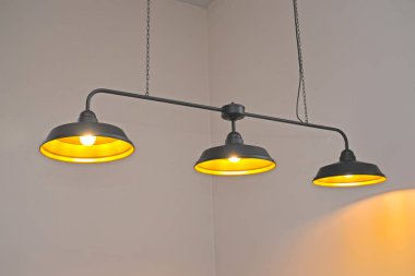 Pendant three-lamp metal lamp on the background of the wall