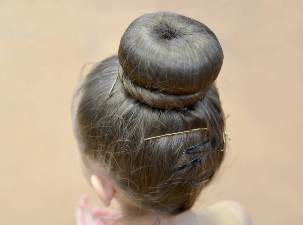 Classic bundle using a roller. Hair of young gymnast, rear view
