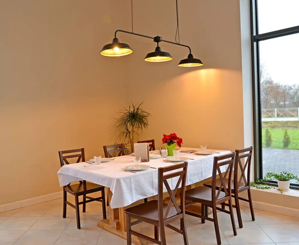 Фрагмент интерьера кафе со столом на шесть человек и подвесной лампой — стоковое фото