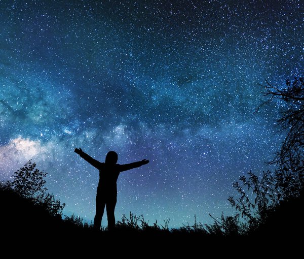 Девушка смотрит на звезды в ночном небе
