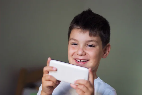 Enfant utilisant un téléphone intelligent mobile et souriant — Photo