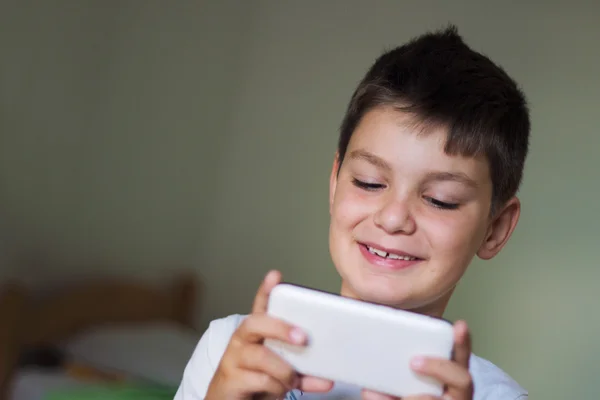 Enfant utilisant un téléphone intelligent mobile et souriant — Photo