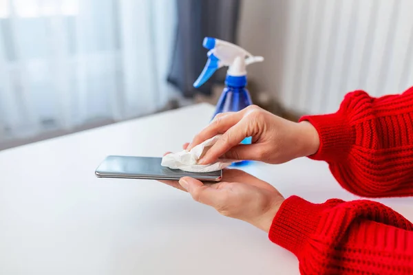 Woman hands with Alcohol Sanitizer mobile phone prevent the virus and bacterias, Hygiene concept. Woman disinfecting the mobile phone by spraying a blue sanitizer from a bottle.Prevent covid19, corona virus.