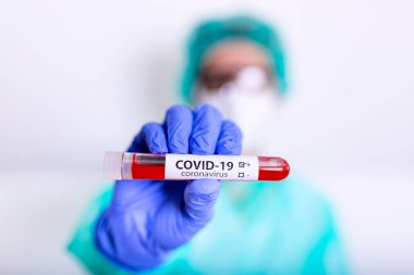 COVID-19, Corona Virüsü veya Roman Coronavirüs salgını. PPE 'de çalışan doktor veya laboratuvar teknisyeni, hastane laboratuvarında kan tüpü testi yapıyor.