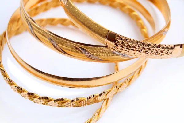 Beyaz arka planda çeşitli altın bilezikler