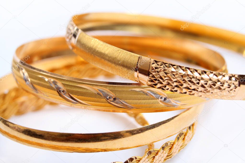 various gold bracelets on a white background