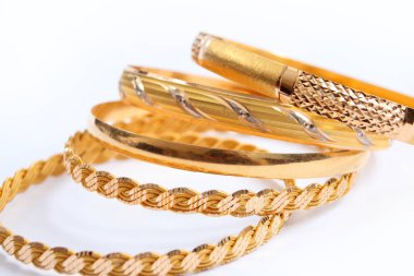 Beyaz arka planda çeşitli altın bilezikler