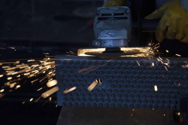 Elektrikli testereyle metal öğüten tanınmayan bir metal işçisi..