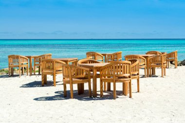 Ahşap masa ve sandalyeler tropikal restoranın kum üzerinde