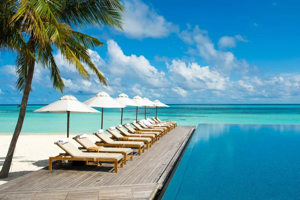 Gran piscina infinita a orillas del Océano Índico con sunbe — Foto de Stock
