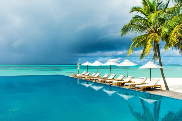 Gran piscina infinita a orillas del Océano Índico con sunbe — Foto de Stock