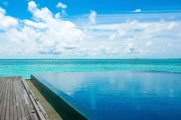 Gran piscina infinita a orillas del Océano Índico con sunbe — Foto de Stock