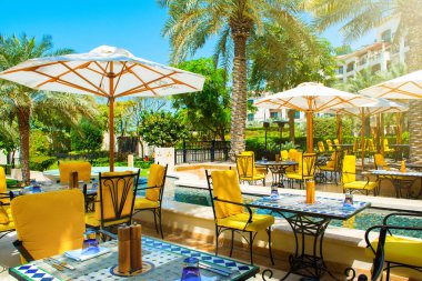 ADU Dhabi, Birleşik Arap Emirlikleri - 27 Mart 2018: palmiye ağaçları ve lagün havuzu ve parlak mobilya, St. Regis Saadiyat Adası Resort şemsiye altında Açık Restoran 