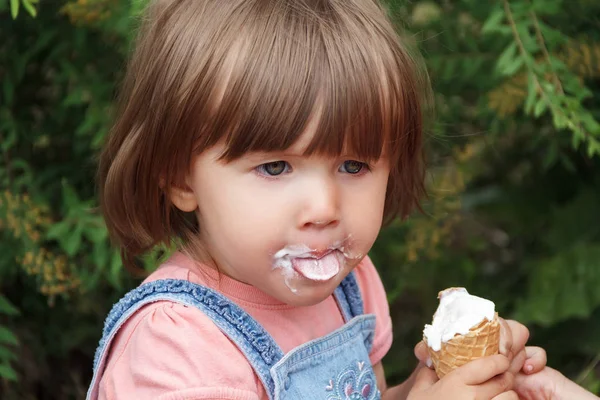 Bebê está comendo gelado com língua apagada — Fotografia de Stock