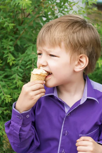 Blond boy are eating icecream with put out tongue — Stock Photo, Image