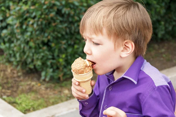 Blond boy are eating icecream with put out tongue — Stock Photo, Image