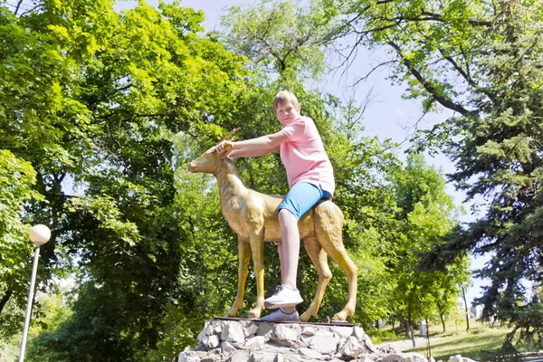 Boy in pink shirt sitting on a golden goat — Stock Photo, Image