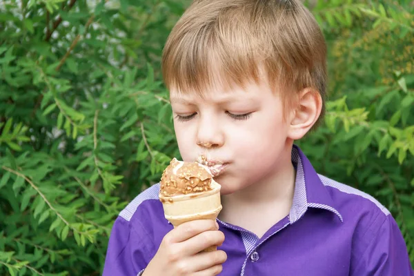 Blond boy are eating icecream with put out tongue — Stock Photo, Image