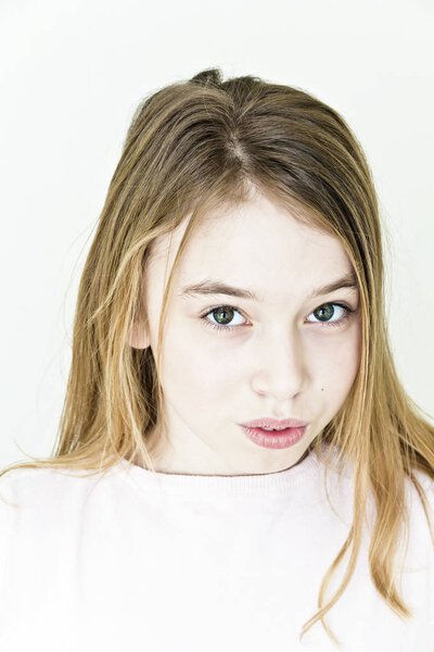 Teenager girl with blond long hair and big eyes on white wall