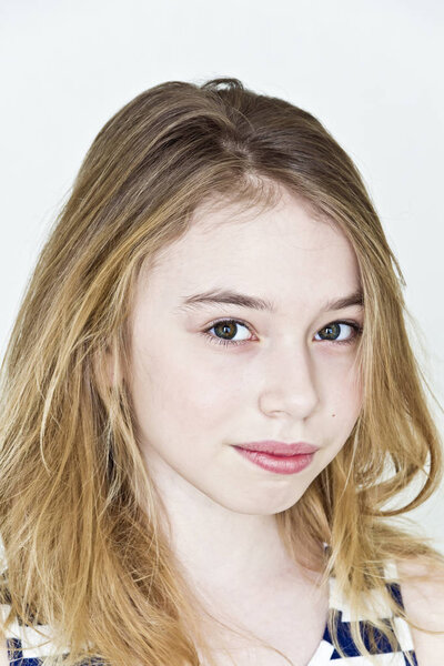 Teenager girl with blond long hair and big eyes on white wall