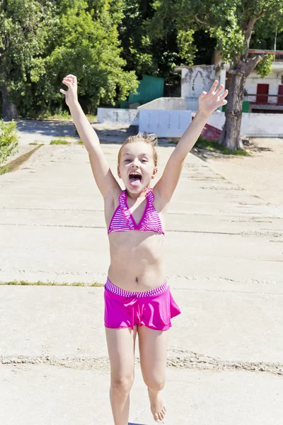 Lopende en gillende meisje in roze badpak — Stockfoto