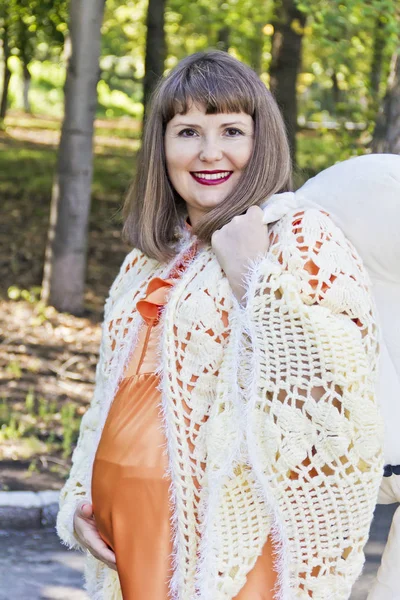 Smiling pregnant woman in orange outdoors — Stock Photo, Image