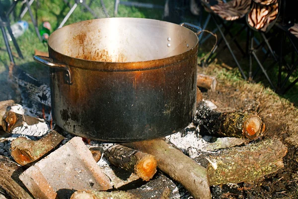 Preparing food  in kettle on campfire — Stock Photo, Image