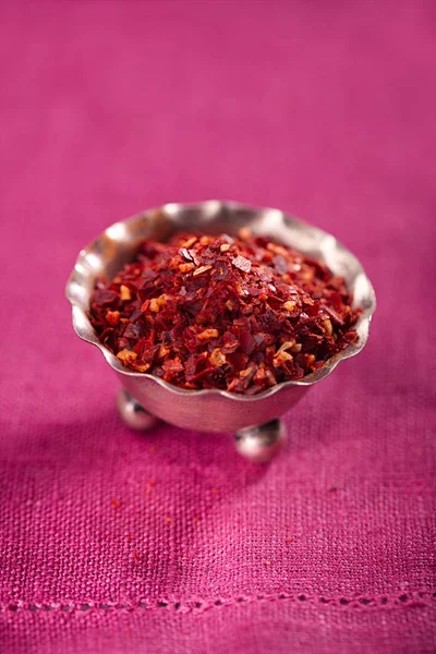 pile of harissa spice mix in small metal bowl on pink cloth, traditional Moroccan red hot chilli mix
