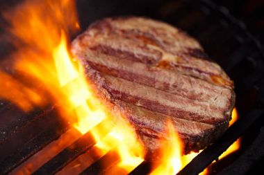ribeye rib eye roast beef steak on bbq barbecue grill with flame. Shallow dof. clipart