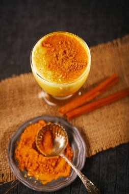 Altın süt zerdeçal latte çanak üzerinde toz tarçın ve çul üzerinde sopa ile