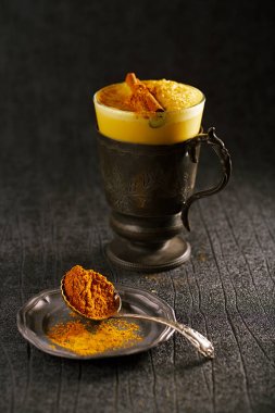 Altın süt zerdeçal latte çanak üzerinde tarçın sopa ve baharat karışımı ile
