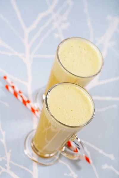 Golden milk turmeric latte in glasses with striped straws on abstract background