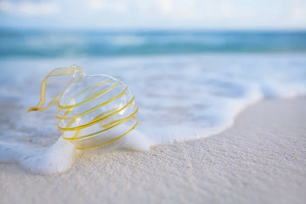 Clear christmas glass ball on beach — 스톡 사진