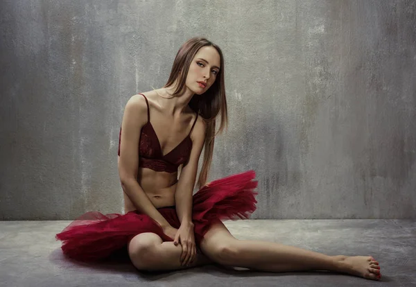 Retrato de jovem dançarina magro em tutu vermelho está sentado em um b — Fotografia de Stock