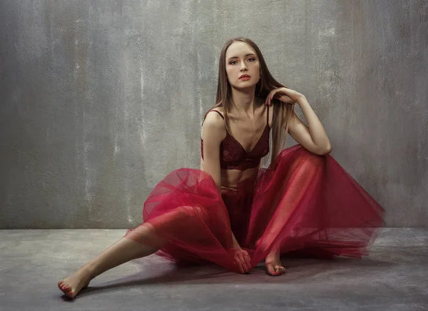 Portrait of slim young girl dancer in red tutu is sitting on a b — Stock Photo, Image