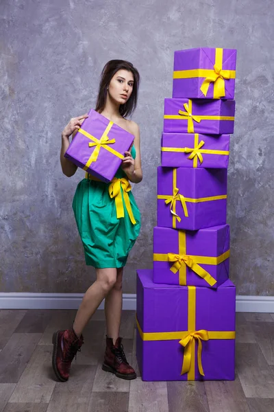 Una giovane ragazza in un vestito e stivali con un regalo in mano, stan — Foto Stock