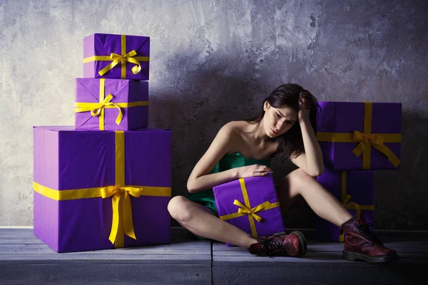 Una giovane ragazza in un vestito e scarpe con un regalo in mano, si siede — Foto Stock