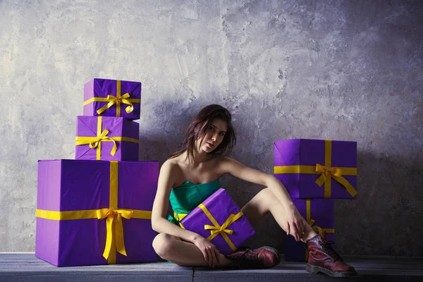 En ung flicka i en klänning och skor med en gåva i händerna, sitter — Stockfoto