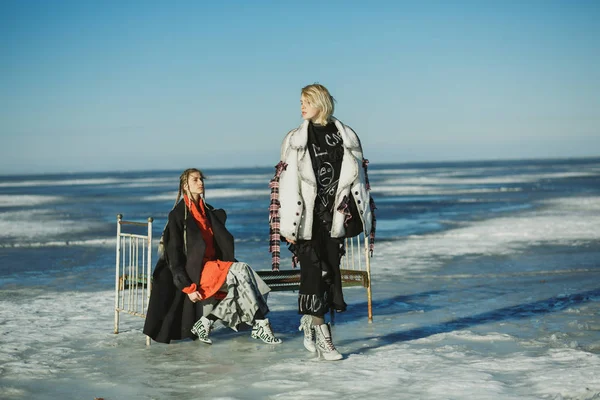 Girls in old clothes with a bed on the frozen sea — Stock Photo, Image