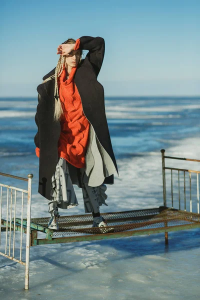 A girl with pigtails in a coat and a big sweater is standing on — Stock Photo, Image