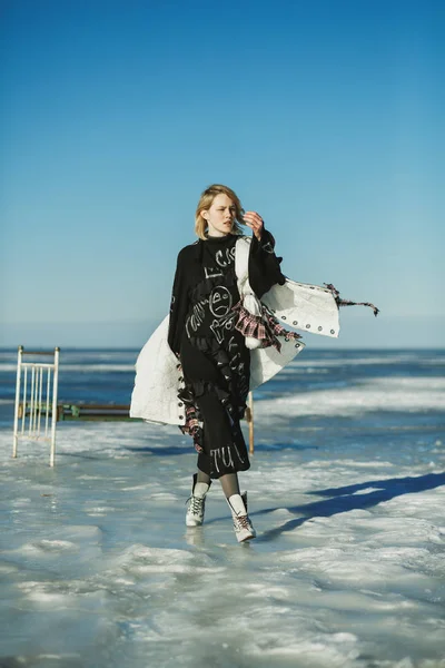 A girl in old clothes walks on ice against the frozen sea and an — Stock Photo, Image