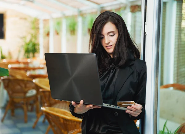 Donna d'affari in piedi nel ristorante con computer portatile e auto di credito — Foto Stock