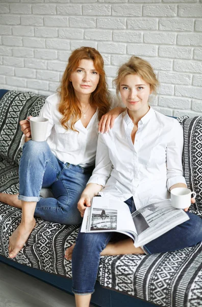 Şık anne ve kızı bir magazin kanepenin üstünde oturuyor — Stok fotoğraf