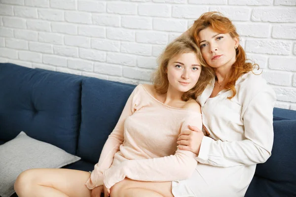 Stylish mommy with her daughter sitting on the couch against a w — Stock Photo, Image