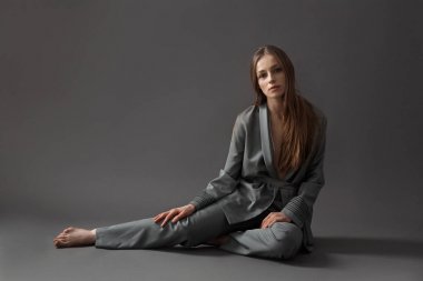 bir kadın gri pijama gri bir arka plan üzerinde oturur