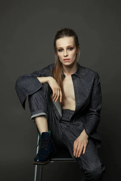 Artistic portrait of a woman in a denim suit on a gray backgroun — Stock Photo, Image