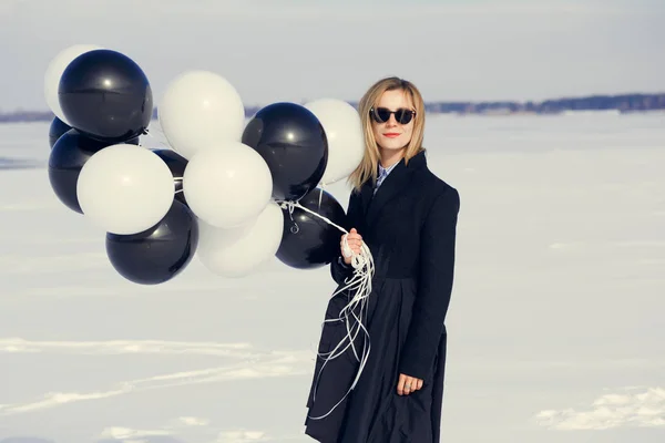 A woman with balloons is having fun in the winter on a snowy bac — Stock Photo, Image